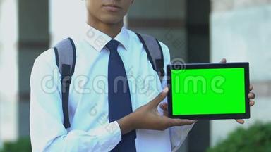 学生<strong>展示</strong>带有绿色屏幕的平板电脑，为电子书<strong>图书</strong>馆应用程序做广告